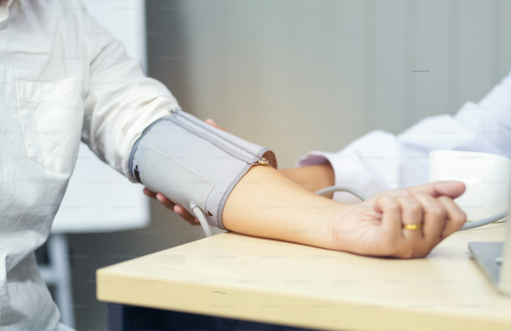 Healthcare professional checking patient's blood pressure with a cuff around the upper arm, monitoring cardiovascular health.